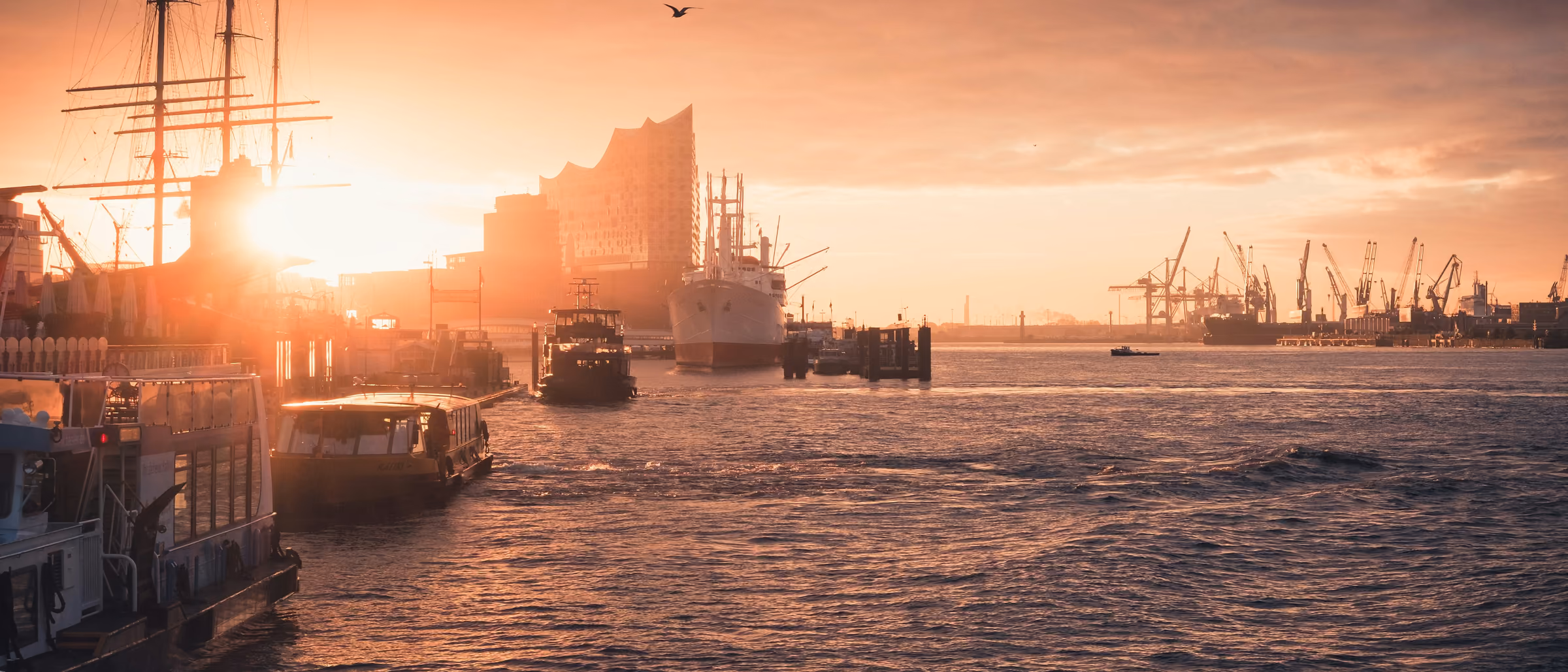 Sonnenuntergang über dem Hamburger Hafen mit Schiffen auf der Elbe