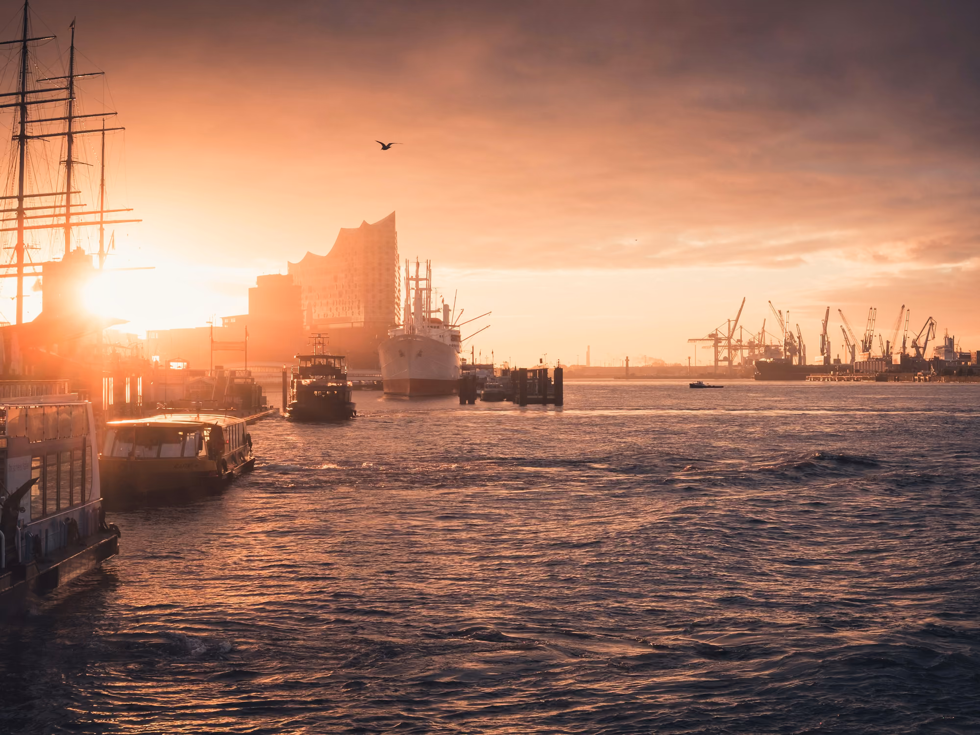 Sonnenuntergang über dem Hamburger Hafen mit Schiffen auf der Elbe