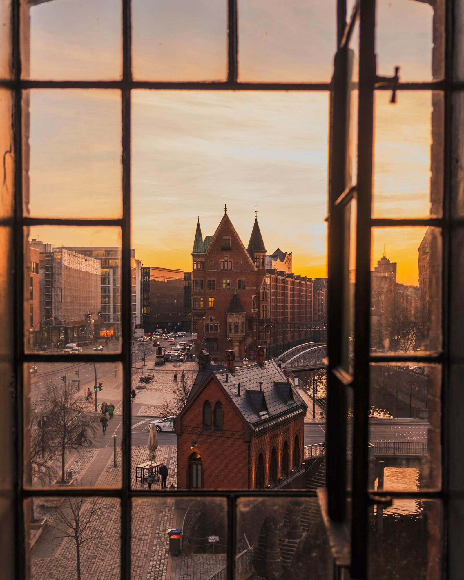 Blick durch ein Sprossenfenster auf Backsteinhäuser in Hamburg im Abendlicht